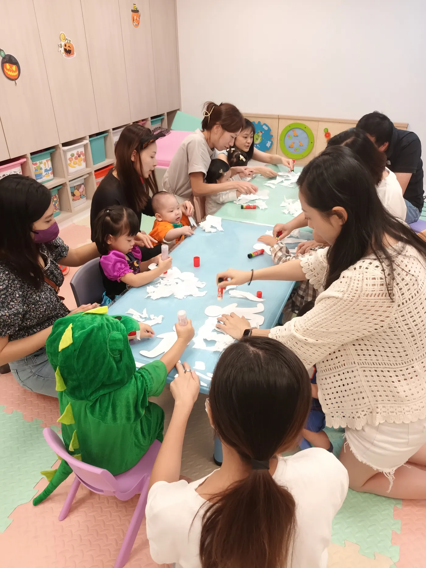 Parents and children making crafts together around a table.