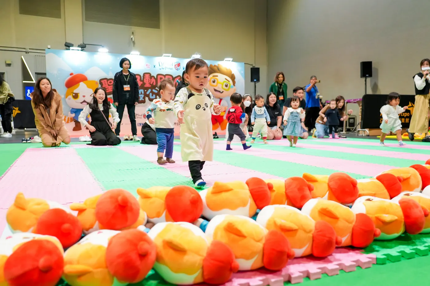 A toddler carrying a toy during a family competition.