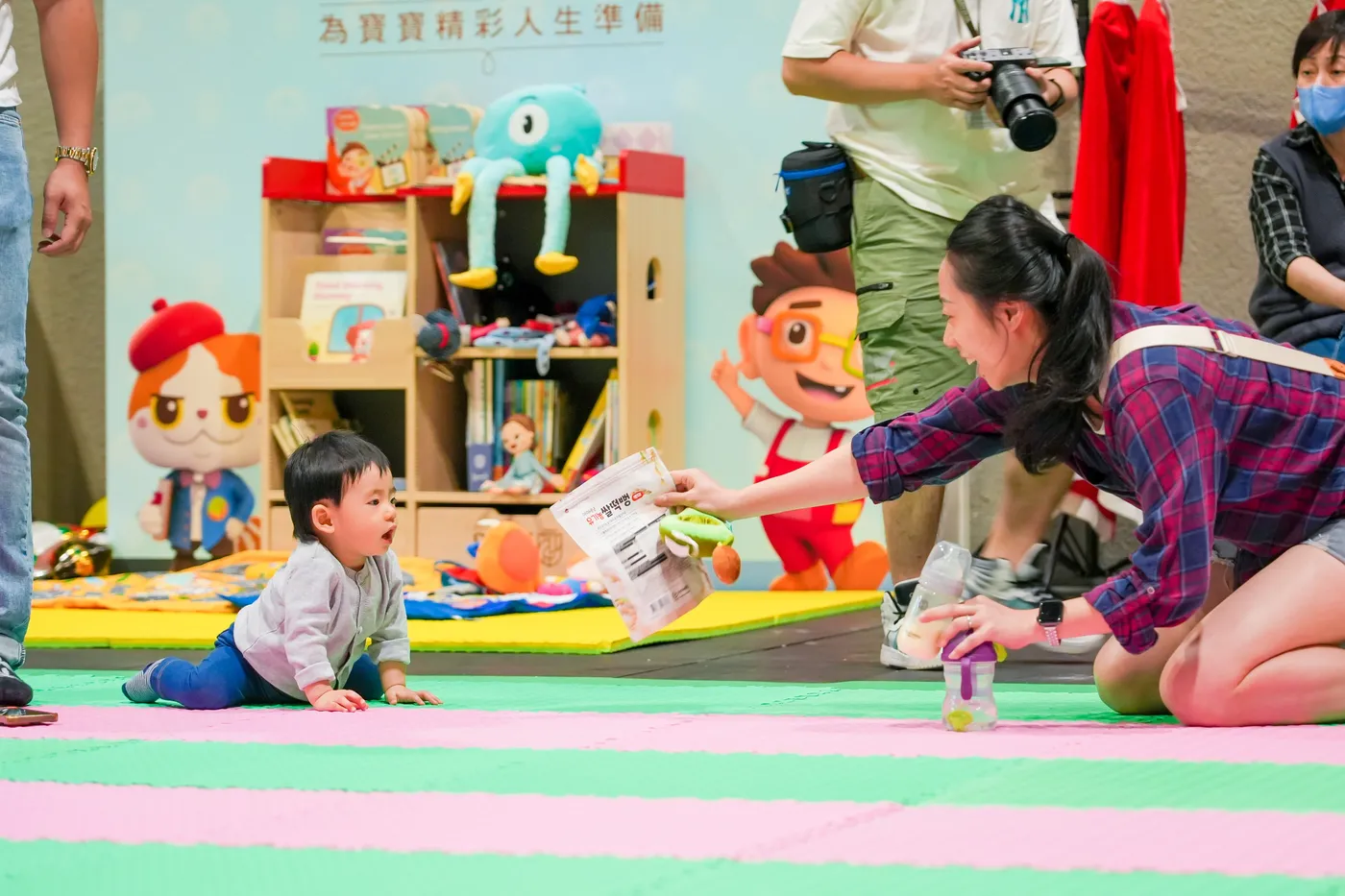 A parent encouraging a baby with a book during a crawling race.